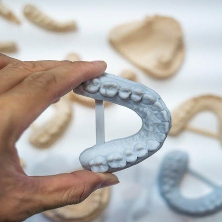 Dental technician modeling frame for implant production from a 3d printer. Image Credit: Shutterstock.com/asharkyu